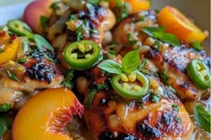 a white plate topped with chicken and fruit covered in sauce, garnished with green leaves