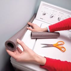 a woman is holding a roll of felt next to a washer with scissors on it