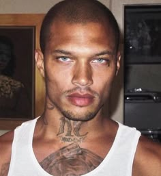 a man with tattoos on his neck and chest standing in front of a framed photo