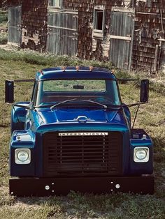 an old blue truck is parked in the grass