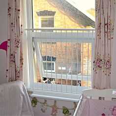 a baby crib in front of a window with pink curtains