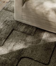 a close up of a rug on the floor near a couch and coffee table in a living room