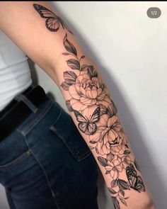 a woman's arm with flowers and butterflies tattoo on the left side of her arm