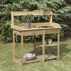 a potting bench in the middle of a yard with plants on it and a bowl next to it