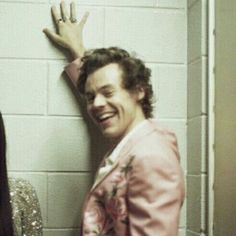 a man in a pink suit standing next to a woman with her hand on the wall