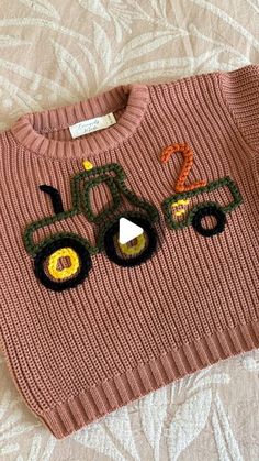 a pink sweater with tractor appliques on it