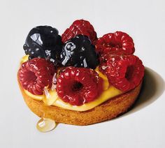 a cake topped with berries and blackberries sitting on top of a white countertop