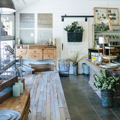 a room filled with lots of wooden furniture and potted plants on top of shelves