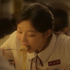 a woman eating noodles with chopsticks in her mouth