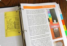 an open book sitting on top of a wooden table next to a pen and paper