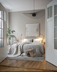 a bedroom with white walls and wood flooring has a large painting on the wall