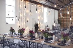 a long table with chairs and lights hanging from it's ceiling in a room