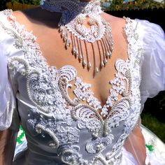 the back of a woman's wedding dress with an elaborate necklace on her neck