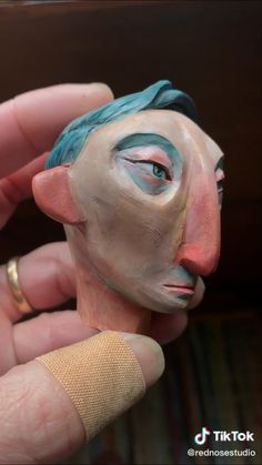 a person is holding a clay face sculpture