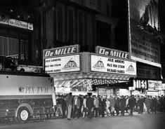 an old black and white photo of people standing in front of a movie theater