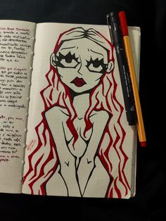 an open notebook with a drawing of a woman's face and red flames on it