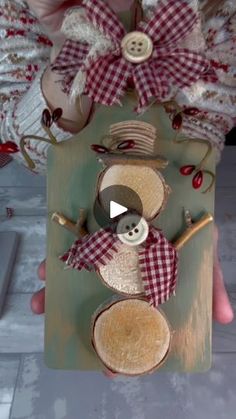 someone is holding up a wooden snowman ornament with red and white gingham