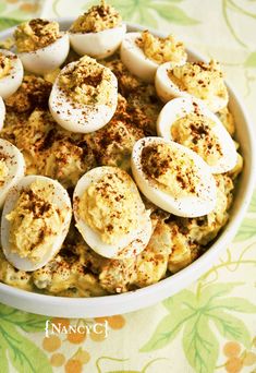 a bowl filled with deviled eggs and cinnamon sprinkled on the top is sitting on a tablecloth