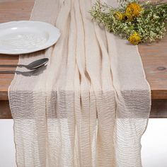 the table is set with a white plate and silverware, along with a bouquet of yellow flowers