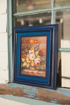 a painting is hanging on the window sill in front of an old wooden frame