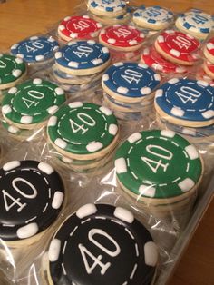 cupcakes decorated with casino chips and numbers are displayed in plastic wrappers on a table