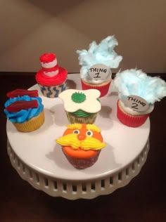 cupcakes decorated to look like characters from the cat in the hat are on a cake plate