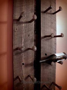 a wine bottle is hanging on a wooden wall with several hooks and screws attached to it