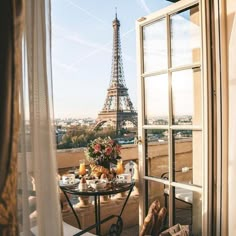 an open window overlooking the eiffel tower and table with food in front of it