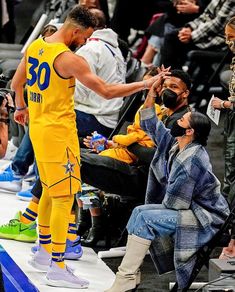 the basketball player is getting his hair combed by an older man in a yellow uniform