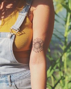 a woman with a sunflower tattoo on her left arm and right arm behind her back