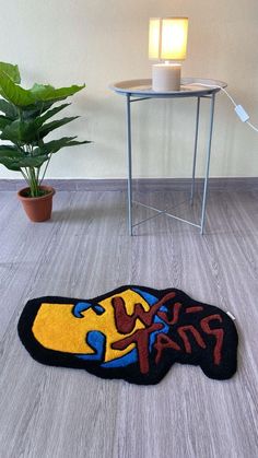 a rug that has been placed on the floor next to a table with a potted plant