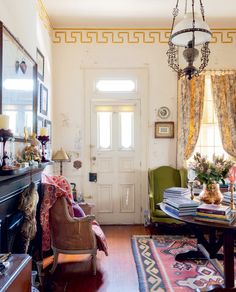 a living room filled with furniture and a fire place under a chandelier hanging from the ceiling