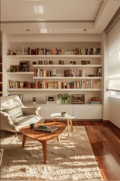 a living room filled with furniture and bookshelves next to a wooden coffee table