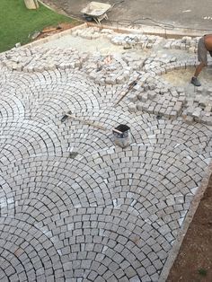 a man laying bricks on the ground