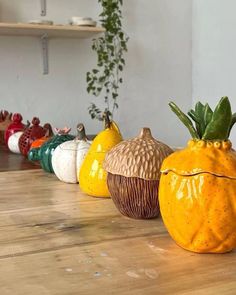 a row of ceramic pumpkins sitting on top of a wooden table