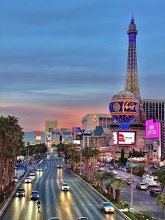 the eiffel tower in las vegas is lit up at night with cars driving down the street