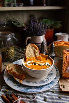 a bowl of soup on a plate with bread in the middle and other dishes around it