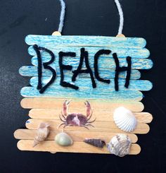 a wooden sign that says beach with sea shells and seashells hanging from it