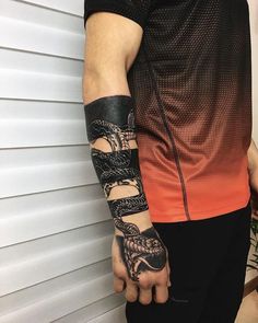 a man with a tattoo on his arm is holding onto a black and white snake