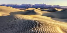 sand dunes in the desert with mountains in the backgrouds and stars in the sky