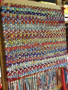 a wall hanging made out of yarn and other items in a room with wood flooring