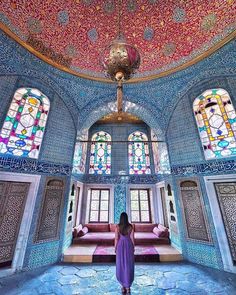 a woman is standing in the middle of a room with stained glass windows