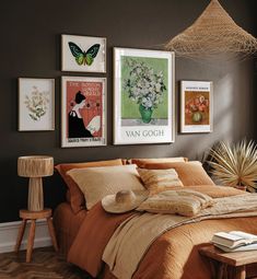 a bedroom with brown walls and pictures on the wall above the bed, along with a lamp