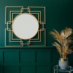 a mirror on the wall above a potted plant in a room with green walls