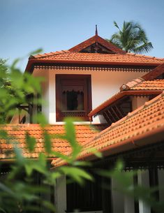 an orange tiled roof on a white house with palm trees in the backgroud