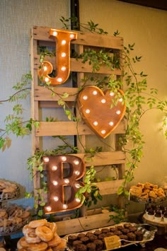 a table topped with lots of pastries and desserts next to a wooden sign