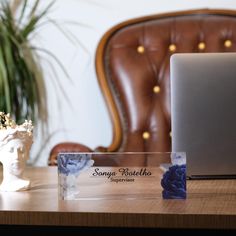 a laptop computer sitting on top of a wooden desk next to a vase with flowers