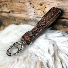 a brown leather keychain with two rings on it sitting on a white fur rug