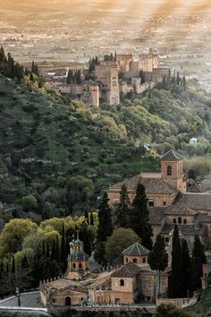 an old castle on top of a hill surrounded by trees and hills in the background