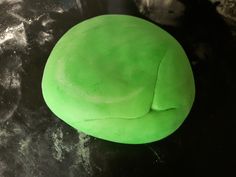 a green round object sitting on top of a black counter next to a metal bowl